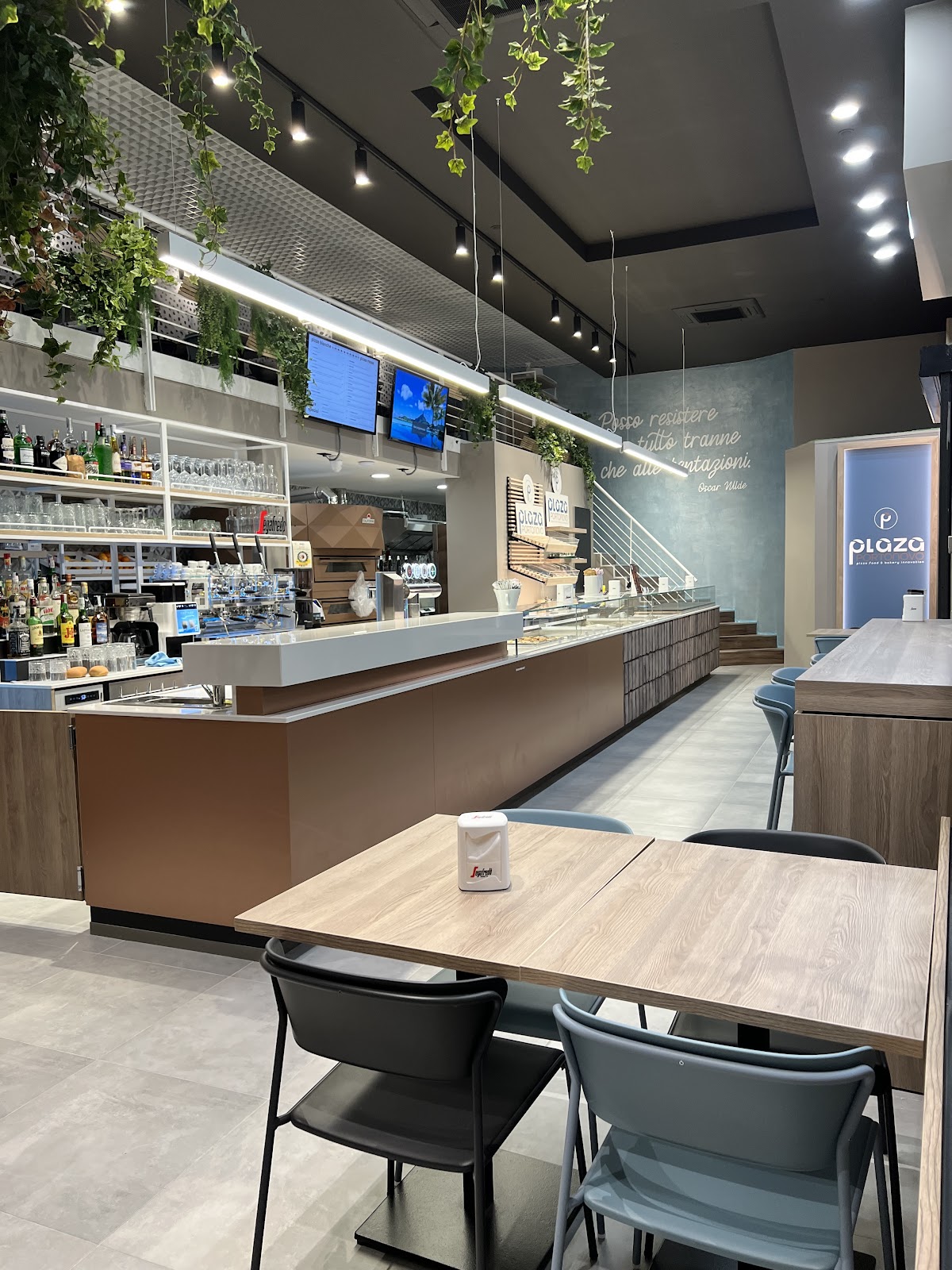 Interno del PLAZA ANCONA con bancone in legno e piante sospese
